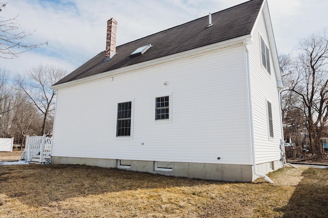 view of side of home featuring a lawn, a chimney, and a shingled roof