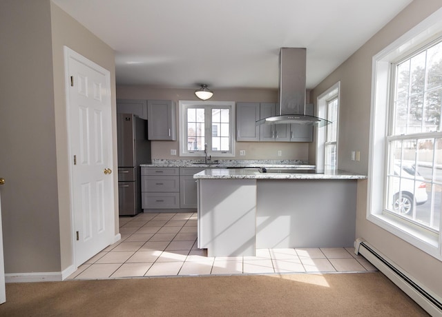 kitchen featuring baseboard heating, gray cabinets, island exhaust hood, freestanding refrigerator, and a sink