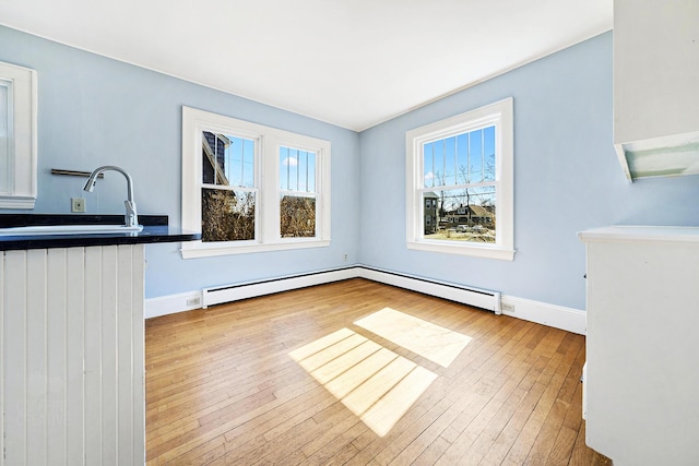 unfurnished dining area with baseboards, wood-type flooring, and a sink