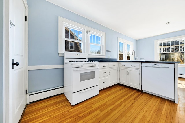 kitchen featuring white appliances, a baseboard radiator, a peninsula, a sink, and light wood-type flooring