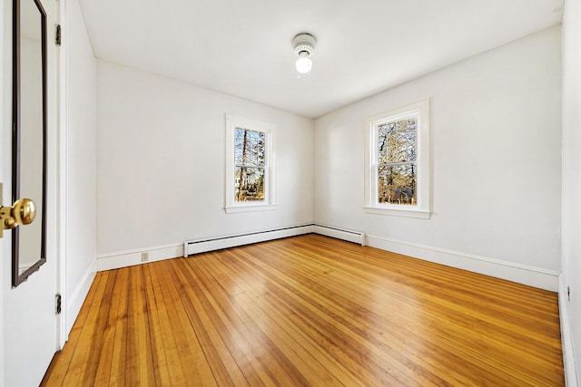 unfurnished room with baseboard heating, baseboards, light wood-style floors, and a healthy amount of sunlight