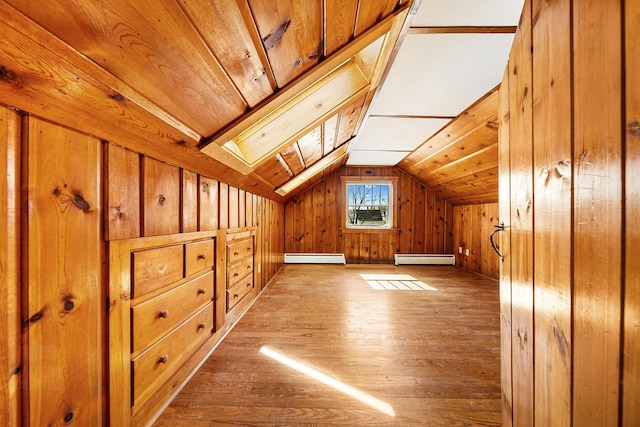 additional living space featuring wood finished floors, wood walls, a baseboard heating unit, lofted ceiling with skylight, and baseboard heating