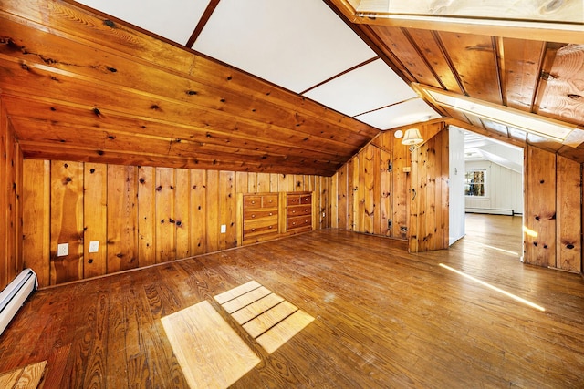 bonus room featuring vaulted ceiling, wooden walls, a baseboard heating unit, and wood-type flooring