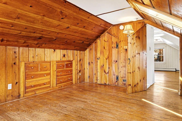 bonus room with a baseboard heating unit, hardwood / wood-style flooring, and wood walls