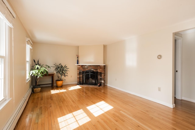 unfurnished living room featuring light wood-type flooring, a baseboard radiator, baseboards, and a brick fireplace