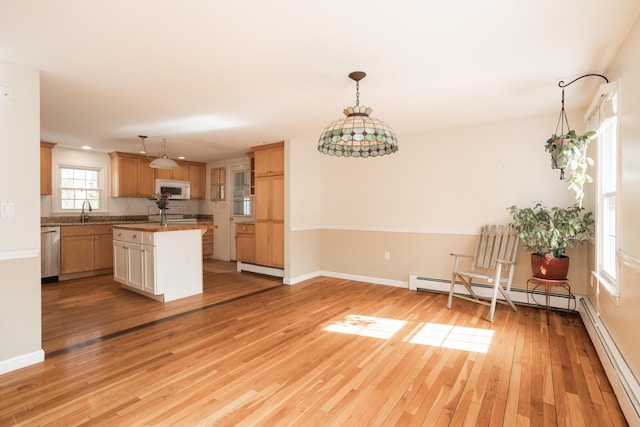 kitchen featuring white microwave, baseboards, stainless steel dishwasher, light wood-type flooring, and baseboard heating