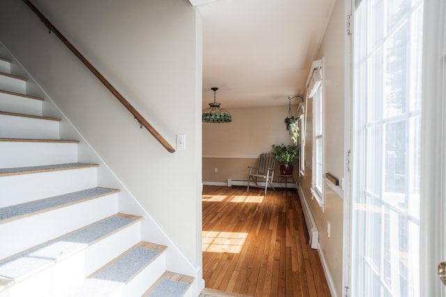 entrance foyer with a baseboard radiator, wood-type flooring, baseboards, and stairway