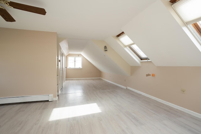 bonus room featuring light wood finished floors, baseboard heating, lofted ceiling with skylight, and baseboards