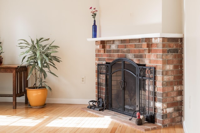 room details with a brick fireplace, baseboards, and wood finished floors