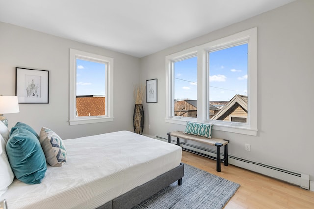 bedroom featuring wood finished floors and a baseboard radiator