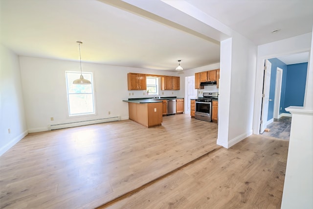 18 Oak St, Camden, ME 04843 - kitchen with baseboard heating, stainless steel appliances, under cabinet range hood, dark countertops, and a peninsula