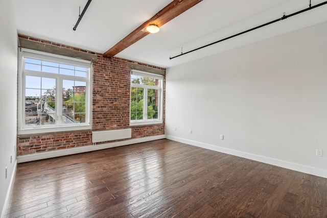 spare room with radiator, baseboards, brick wall, wood-type flooring, and beamed ceiling