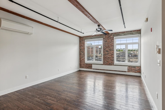 empty room with hardwood / wood-style floors, a wall mounted air conditioner, brick wall, and radiator heating unit