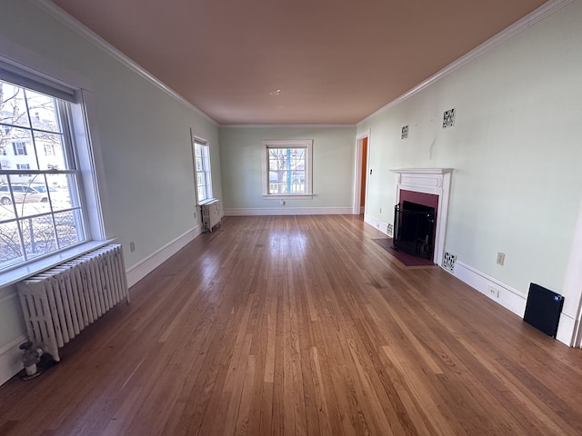 unfurnished living room with radiator, radiator heating unit, wood finished floors, and a fireplace with flush hearth