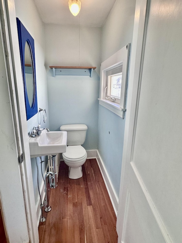 bathroom with toilet, baseboards, and wood-type flooring