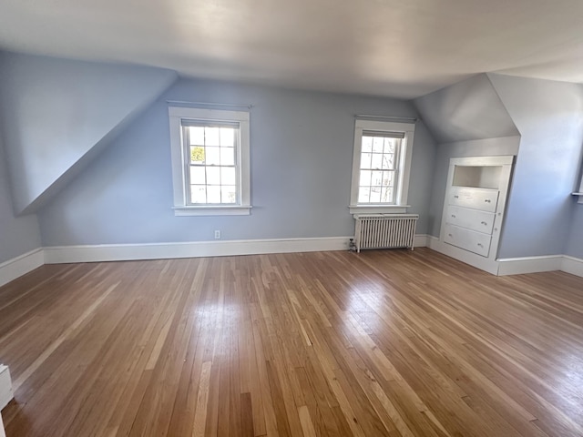 additional living space featuring hardwood / wood-style flooring, radiator heating unit, baseboards, and vaulted ceiling