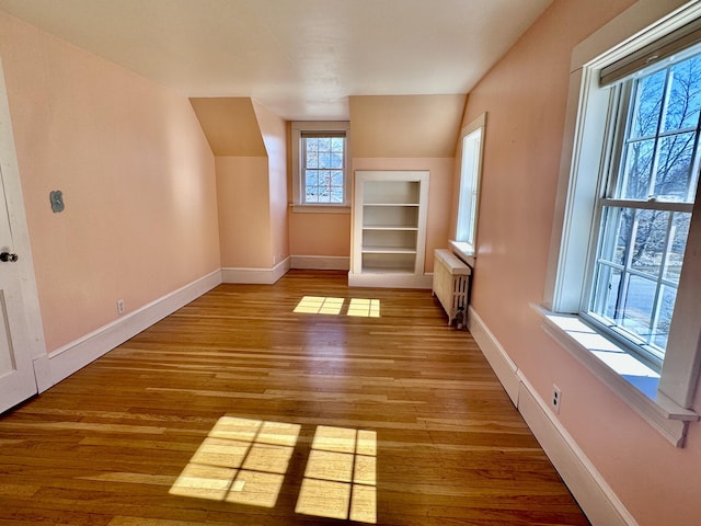 additional living space with built in features, radiator heating unit, and baseboards