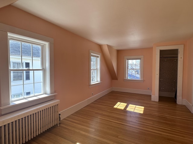 additional living space featuring radiator heating unit, baseboards, and wood finished floors