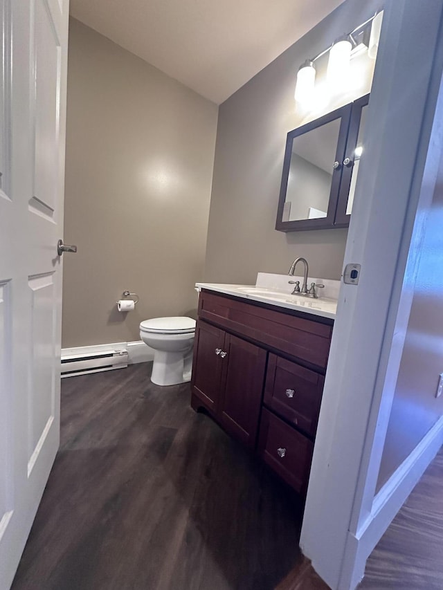 bathroom with vanity, wood finished floors, baseboards, a baseboard radiator, and toilet