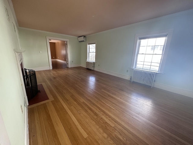 unfurnished living room with light wood-style flooring, radiator, a wall unit AC, and ornamental molding