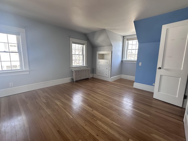 additional living space featuring vaulted ceiling, radiator, baseboards, and wood-type flooring