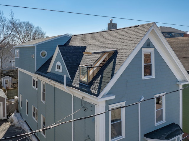 view of property exterior with a chimney, a shingled roof, and a balcony