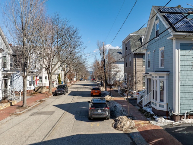 view of street featuring curbs, street lighting, sidewalks, and a residential view