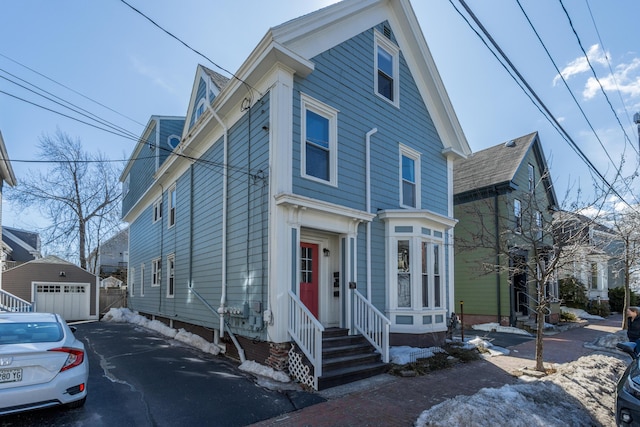 view of front of house with aphalt driveway, a detached garage, an outdoor structure, and entry steps