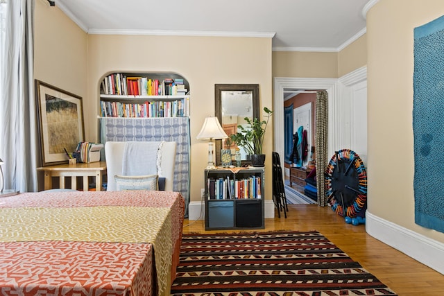 bedroom with crown molding, wood finished floors, and baseboards