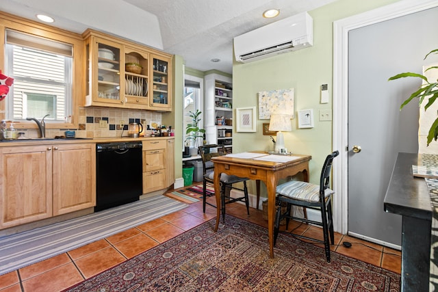 kitchen featuring a wall mounted air conditioner, black dishwasher, a sink, and light tile patterned floors