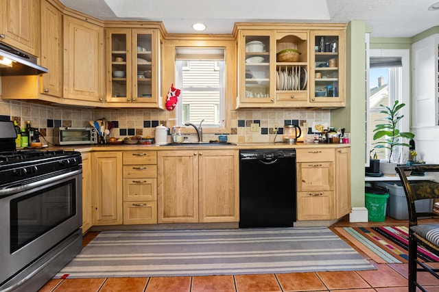 kitchen with stainless steel gas range oven, tile patterned floors, under cabinet range hood, a sink, and dishwasher