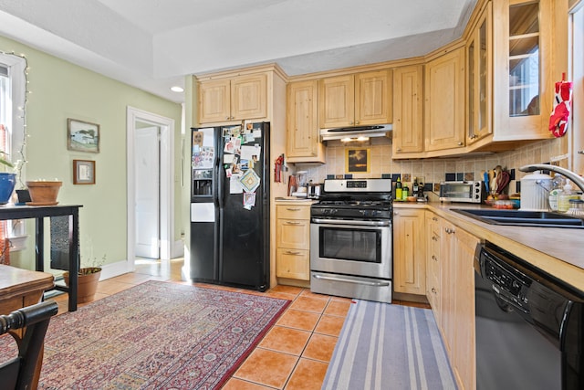 kitchen featuring light brown cabinetry, under cabinet range hood, light tile patterned floors, black appliances, and a sink