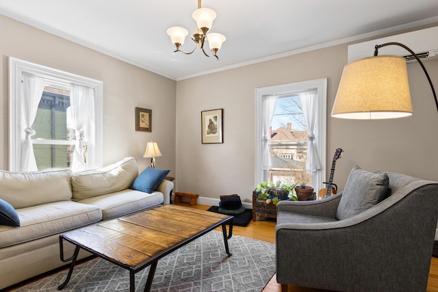 living area with baseboards, a notable chandelier, wood finished floors, and crown molding