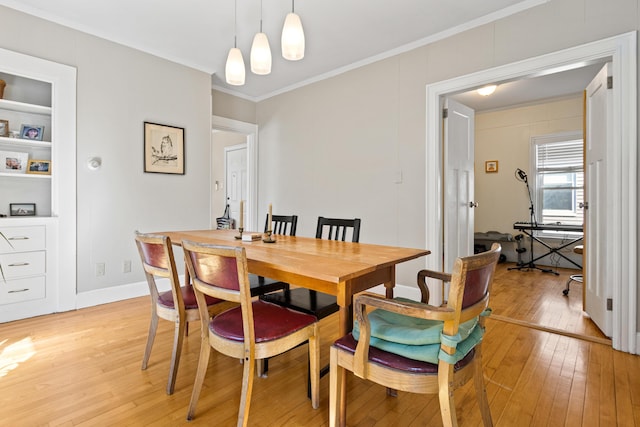 dining space featuring crown molding, light wood-style flooring, and baseboards