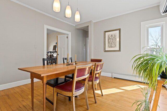 dining room with a baseboard heating unit, crown molding, baseboards, and light wood finished floors