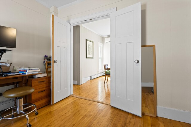 home office featuring a baseboard heating unit, light wood-style flooring, crown molding, and a wall unit AC