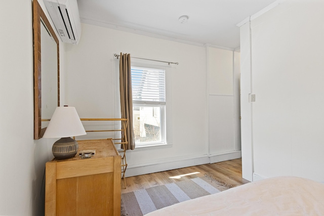 bedroom featuring wood finished floors and a wall unit AC