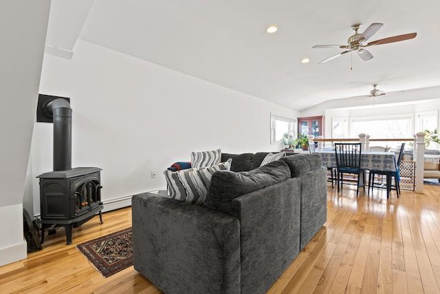 living area featuring a ceiling fan, lofted ceiling, a wood stove, recessed lighting, and light wood-style floors