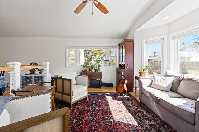 living room featuring vaulted ceiling, a ceiling fan, and wood finished floors