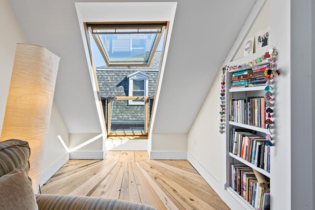 interior space featuring a skylight, baseboards, and wood-type flooring