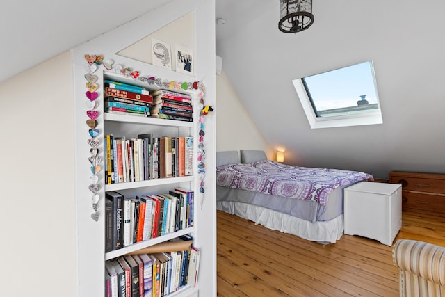 bedroom with vaulted ceiling with skylight and hardwood / wood-style flooring