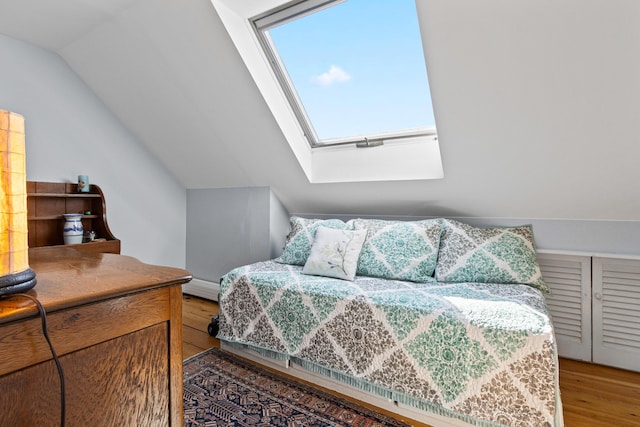 bedroom featuring vaulted ceiling with skylight and light wood finished floors