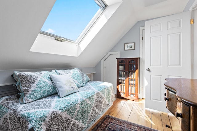 bedroom with lofted ceiling with skylight and wood-type flooring