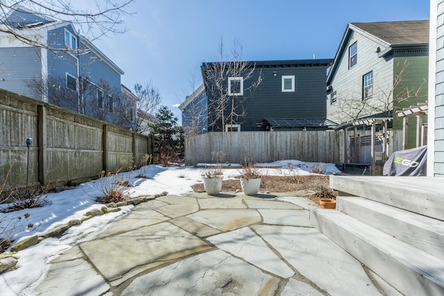 snow covered patio featuring a fenced backyard