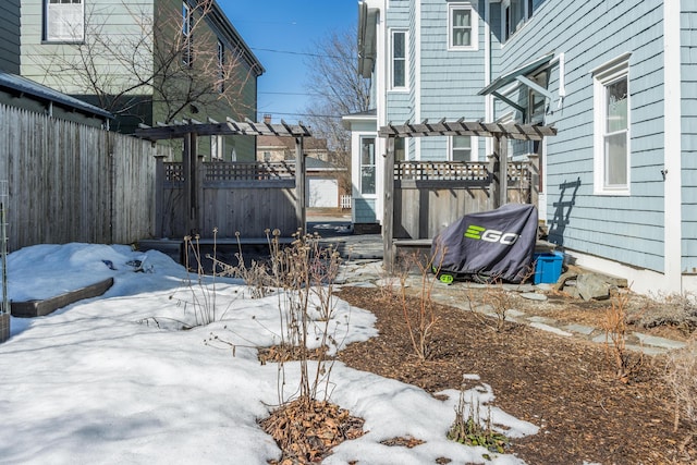 yard layered in snow with a pergola and fence