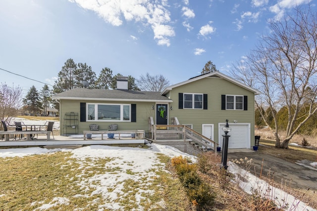 tri-level home with a wooden deck, an attached garage, a chimney, and concrete driveway