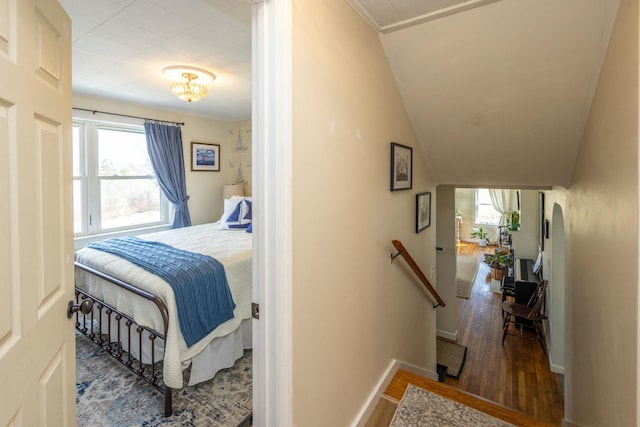 bedroom featuring baseboards, wood finished floors, and vaulted ceiling