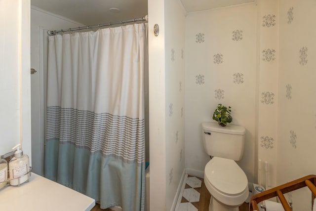 bathroom featuring toilet, a shower with shower curtain, baseboards, and ornamental molding