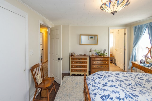 bedroom with ornamental molding and wood finished floors