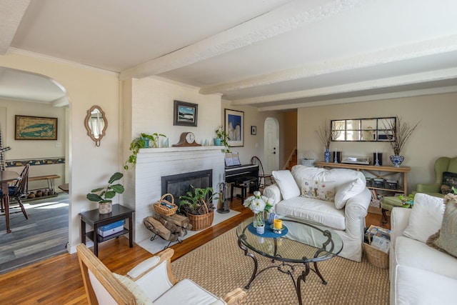 living room with a fireplace with flush hearth, stairs, beam ceiling, wood finished floors, and arched walkways